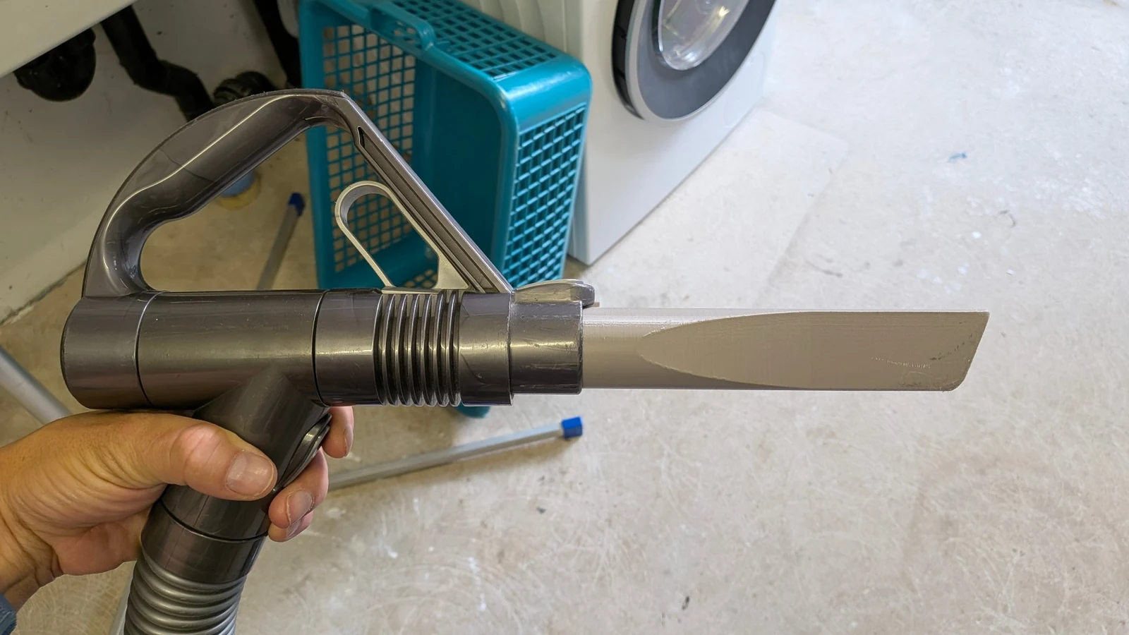 Eine Hand hält einen Dyson-Staubsauger mit der selbst gedruckten schmalen Düse