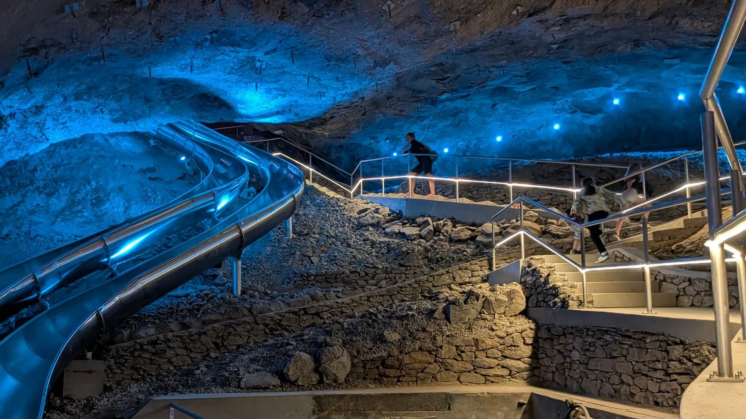 Blau beleuchteter Felsraum mit Treppen und Metallkanälen im Besucherbereich der Salzmine von Bex