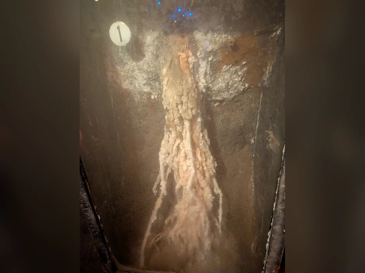 Helle mineralische Salzablagerung in einer dunklen Felswand