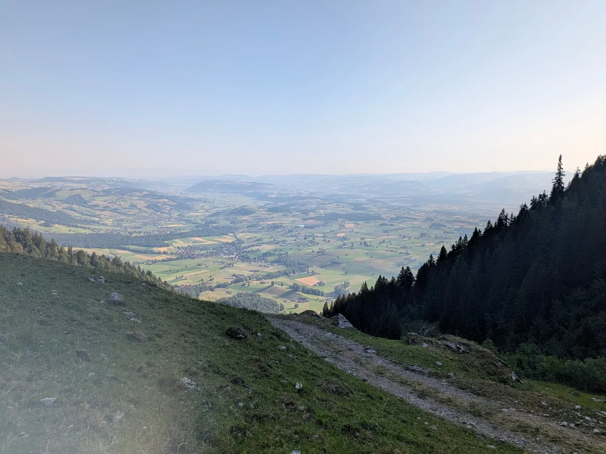 Weiter Blick von einer Alpweide hinunter über Täler und Landschaft